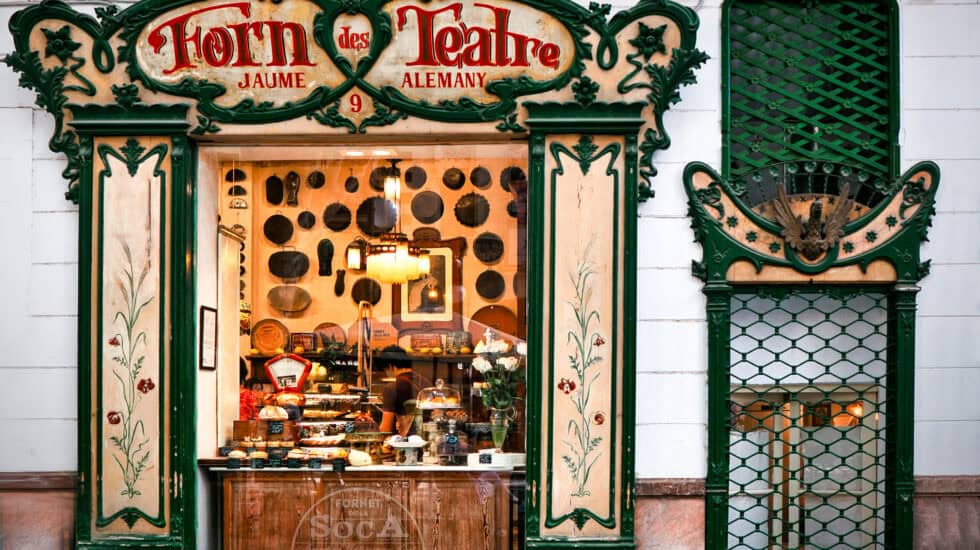 Ornate theatre shop front with decorative green and cream framing, vintage signage, and display window showcasing pastries and desserts, in a traditional European style, exterior shot.