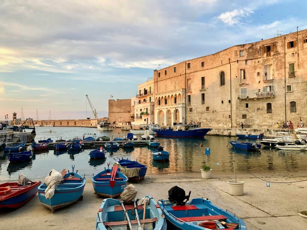 Colourful boats docked in a historic harbour with ancient stone buildings showcasing Mediterranean seaside charm. Perfect for travel lovers exploring coastal destinations in Italy.
