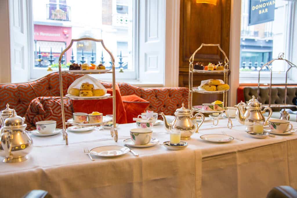 Afternoon tea at The Ritz London with silver teapots, tiered cake stands, and fine china in an elegant setting