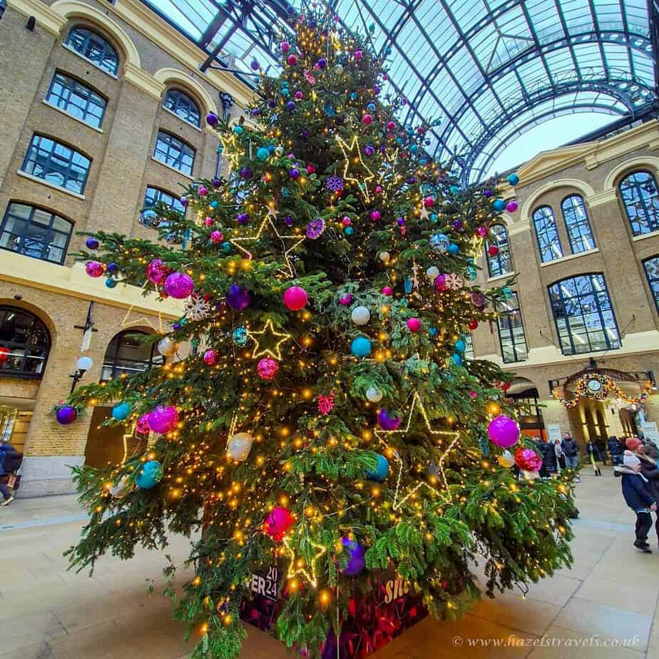 Colourful Christmas tree with purple baubles and star decorations inside Hays galleria in London