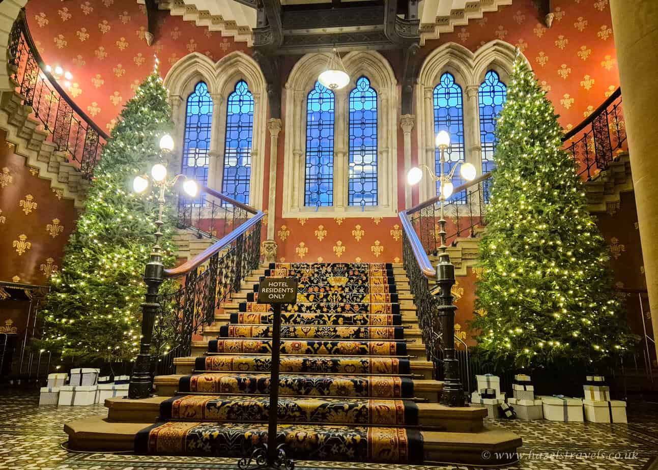 Grand staircase decorated with Christmas trees and golden lights at St Pancras Renaissance Hotel, London