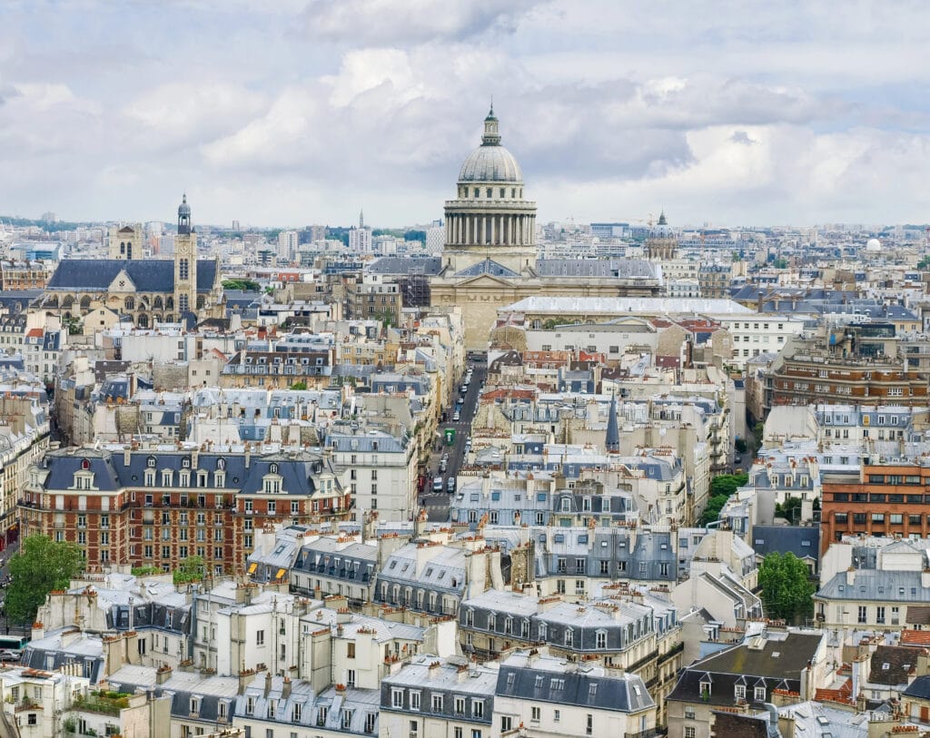 Panoramic view of Paris rooftops with the Panthéon dome in the distance.
