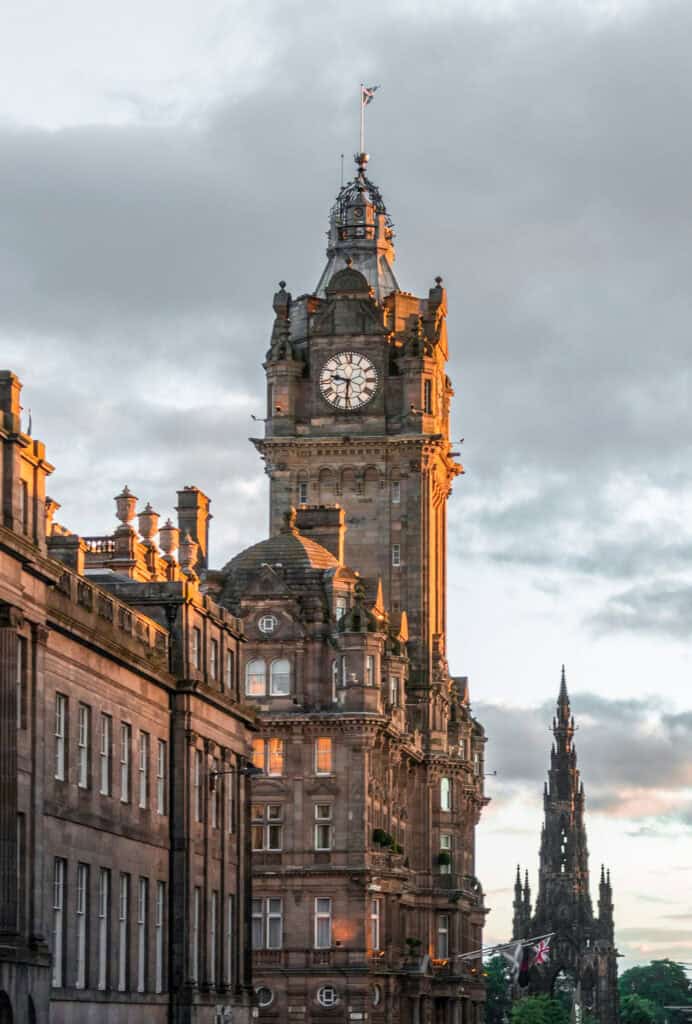 The Balmoral Hotel clock tower and nearby buildings on Princes Street, Edinburgh, on a cloudy day.