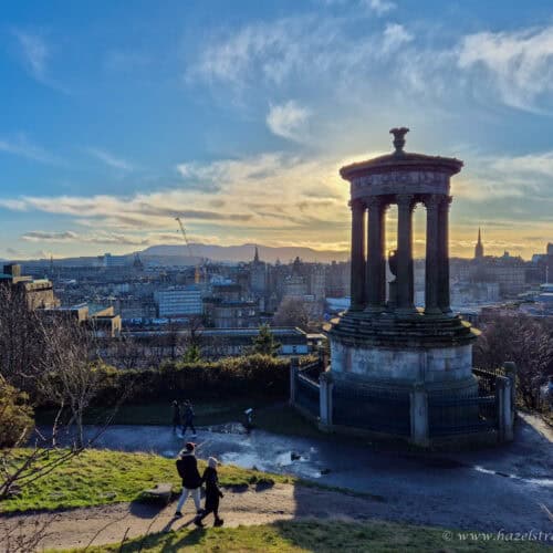 View from Calton Hill with the Dugald Stewart Monument and the Edinburgh skyline at golden hour.