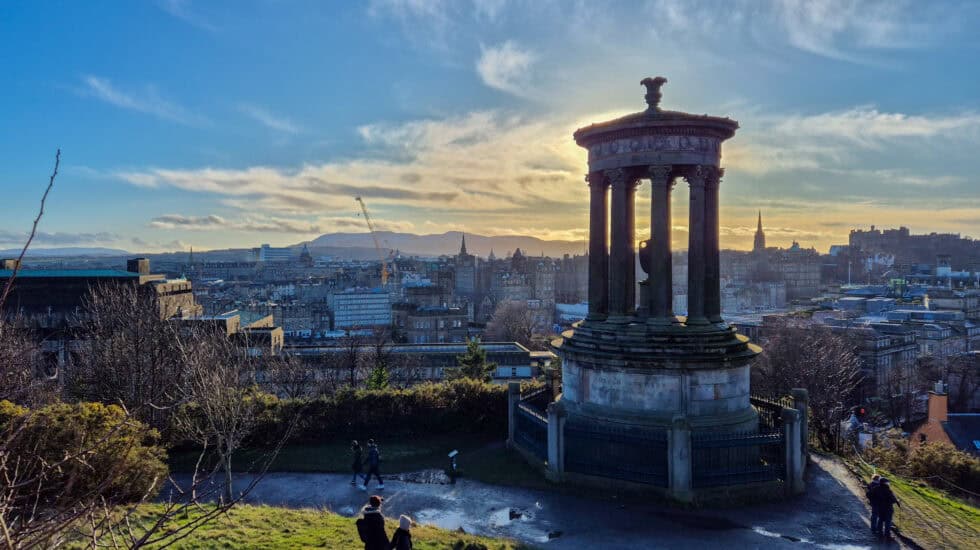 View from Calton Hill with the Dugald Stewart Monument and the Edinburgh skyline at golden hour.
