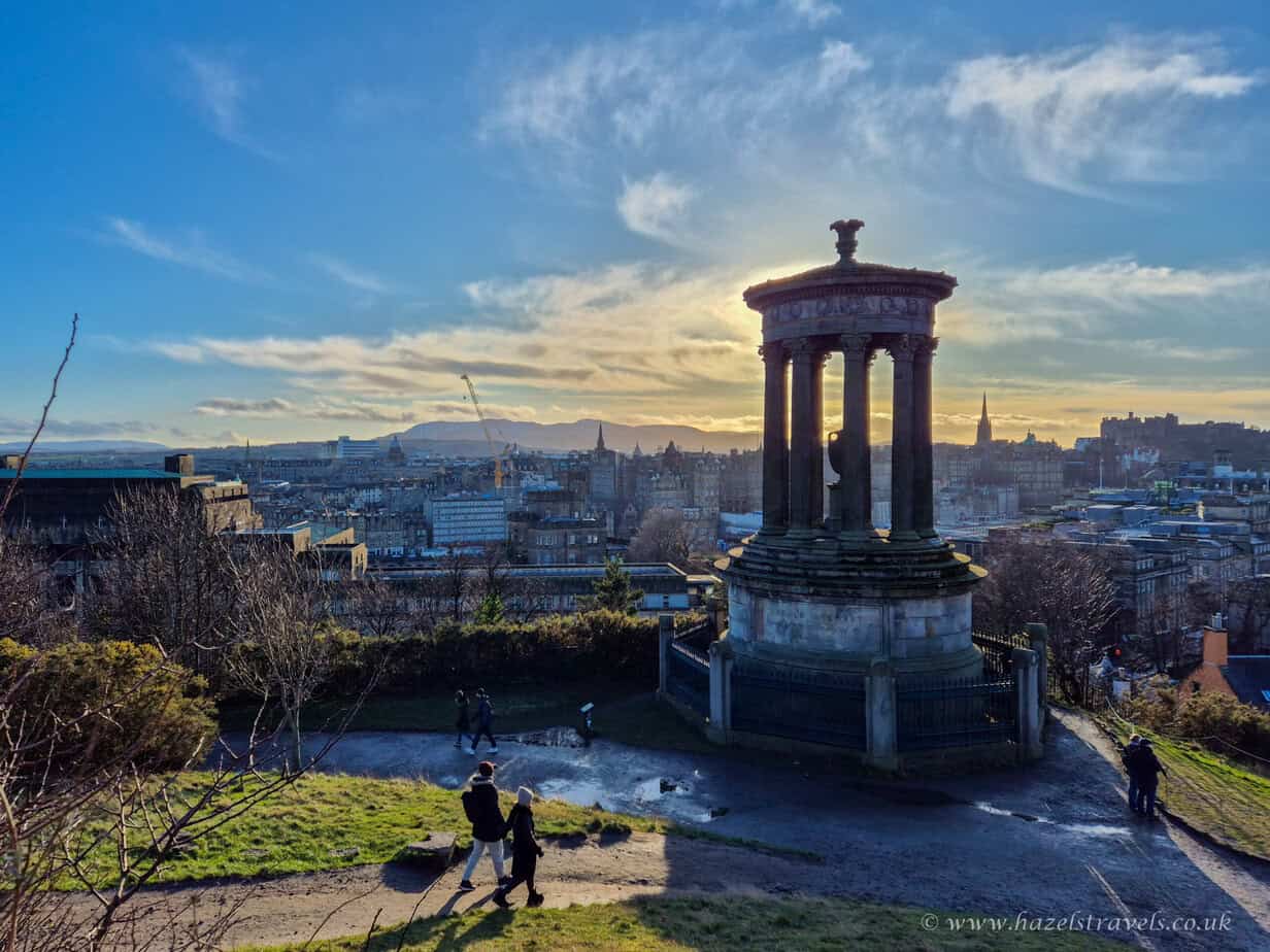 View from Calton Hill with the Dugald Stewart Monument and the Edinburgh skyline at golden hour.