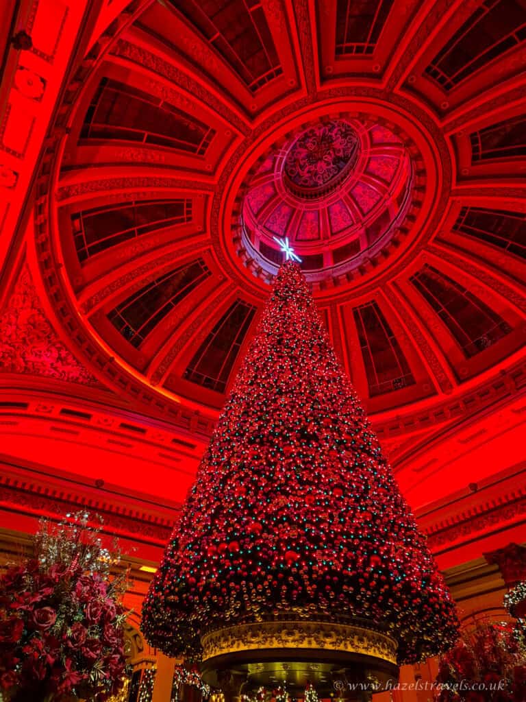 Festive red-lit interior of The Dome in Edinburgh with a towering Christmas tree reaching the ceiling.