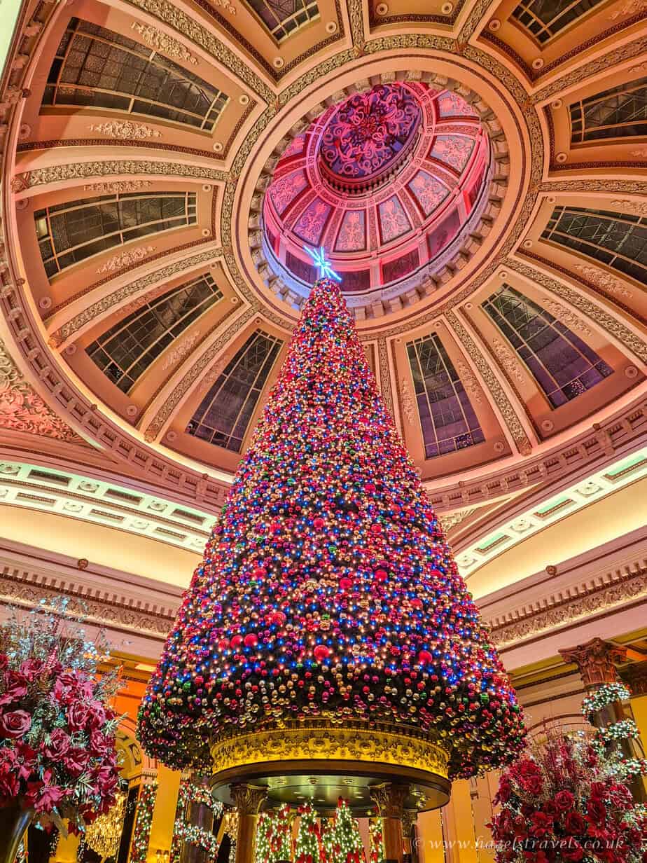 Giant Christmas tree decorated in red and gold lights inside The Dome Edinburgh beneath its ornate domed ceiling.
