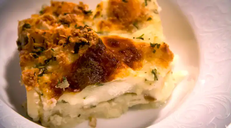 Slice of zuppa gallurese, a traditional Sardinian dish made with layers of bread, pecorino cheese, and broth, baked until golden and crisp on top.