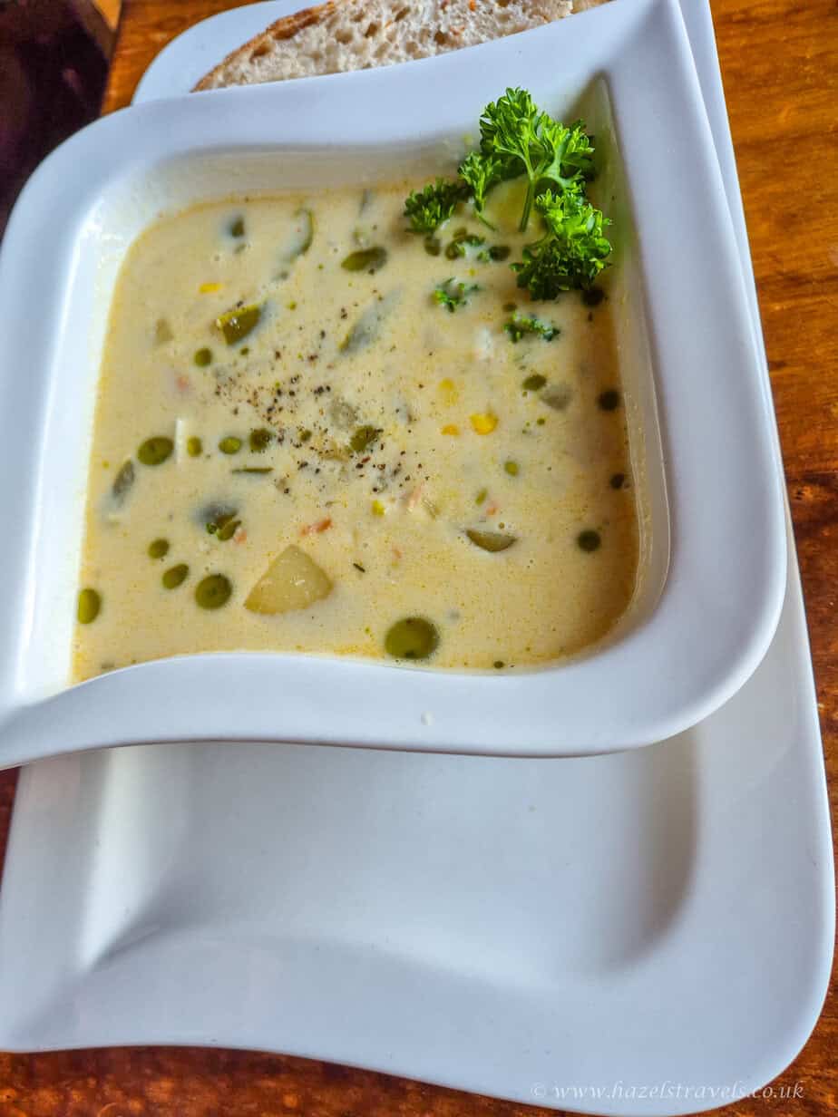 Bowl of creamy Cullen skink soup garnished with herbs, served on a wooden table.