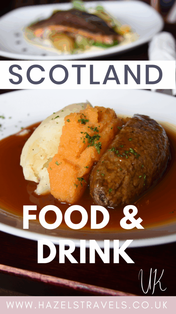 Close-up of a traditional food of Scotland featuring haggis, mashed potatoes, and mashed turnip (neeps and tatties) served with rich brown gravy, with another plate of salmon and vegetables blurred in the background. Text overlay reads “Scotland Food & Drink UK” with the Hazel’s Travels website link at the bottom.