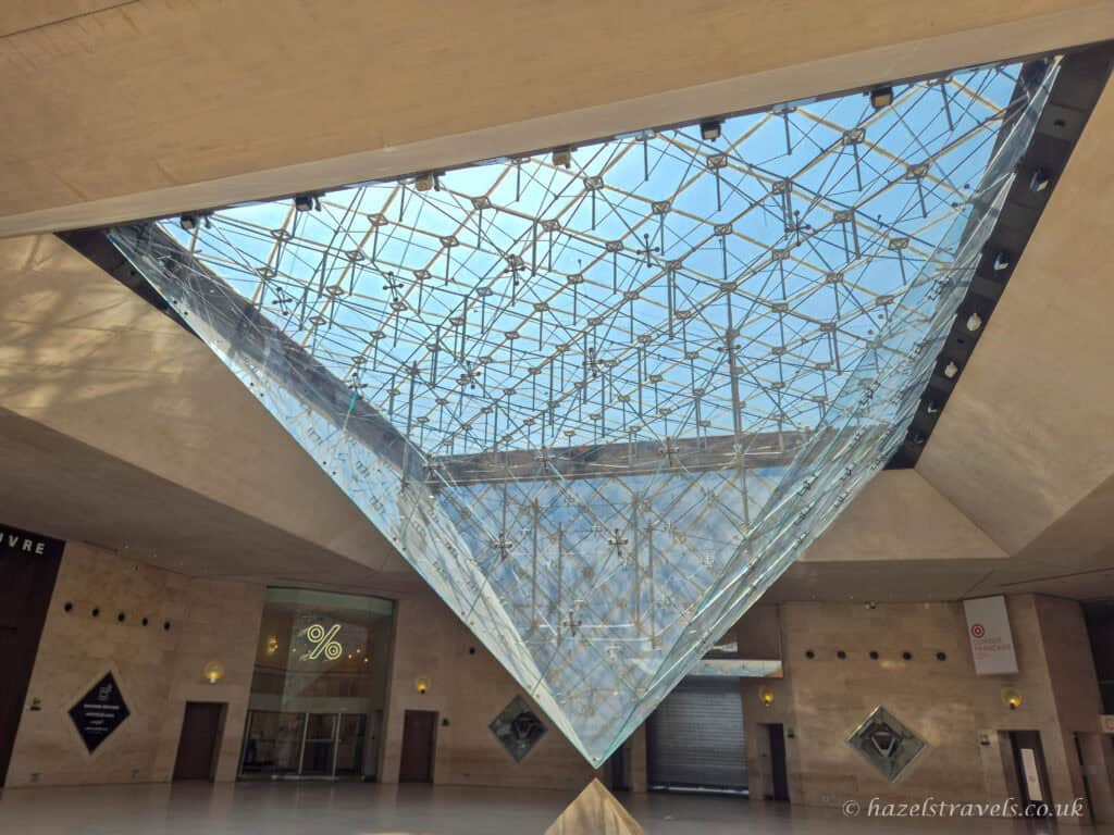Louvre glass pyramid, Paris — View of the Louvre Pyramid’s geometric structure from below, with light streaming in.