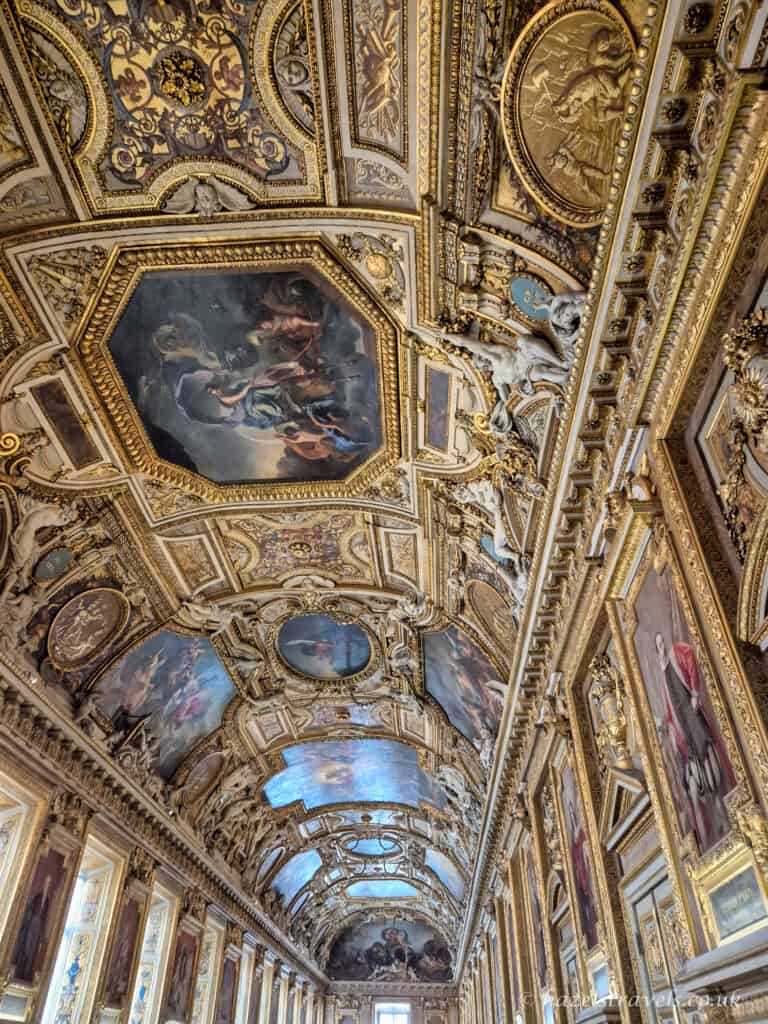 Louvre ceiling frescoes, Paris — Ornate gold and painted ceiling inside one of the Louvre’s grand halls.