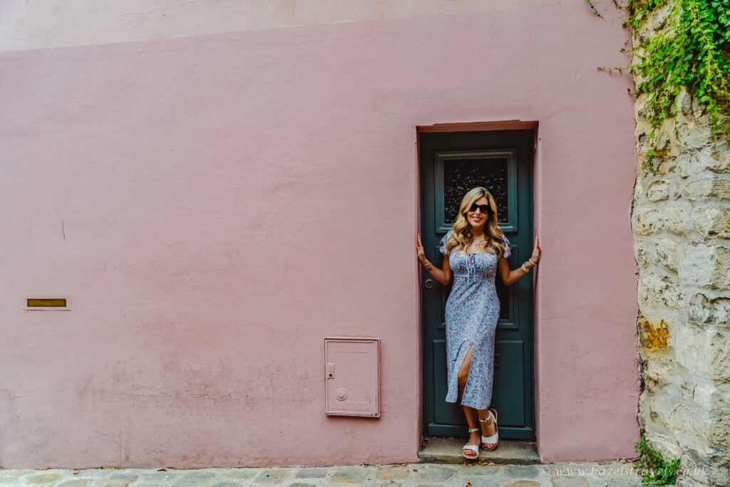 Rue Crémieux, Paris - Woman posing beside pastel pink house on one of Paris’s most colourful streets.