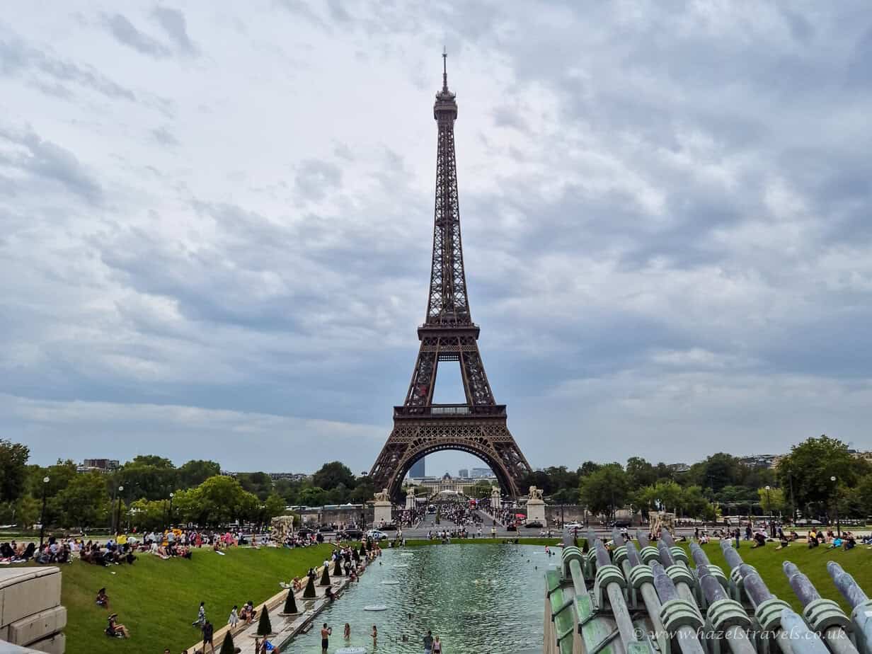 Eiffel Tower, Paris - Full view of the Eiffel Tower rising above the fountains of Trocadéro Gardens under a cloudy sky.