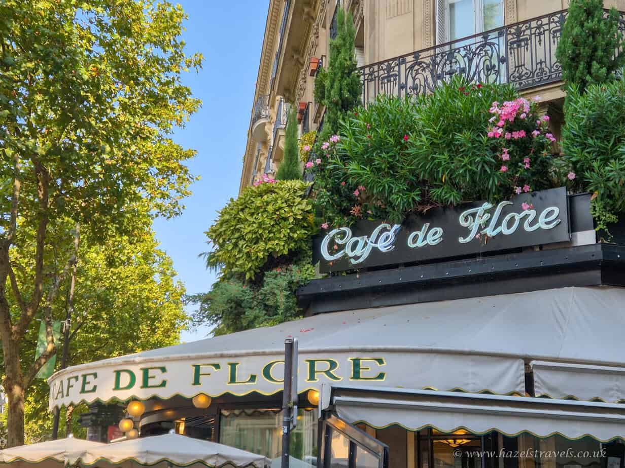 The iconic Café de Flore in Saint-Germain-des-Prés, Paris, with green awnings, floral balconies, and classic Parisian charm.
