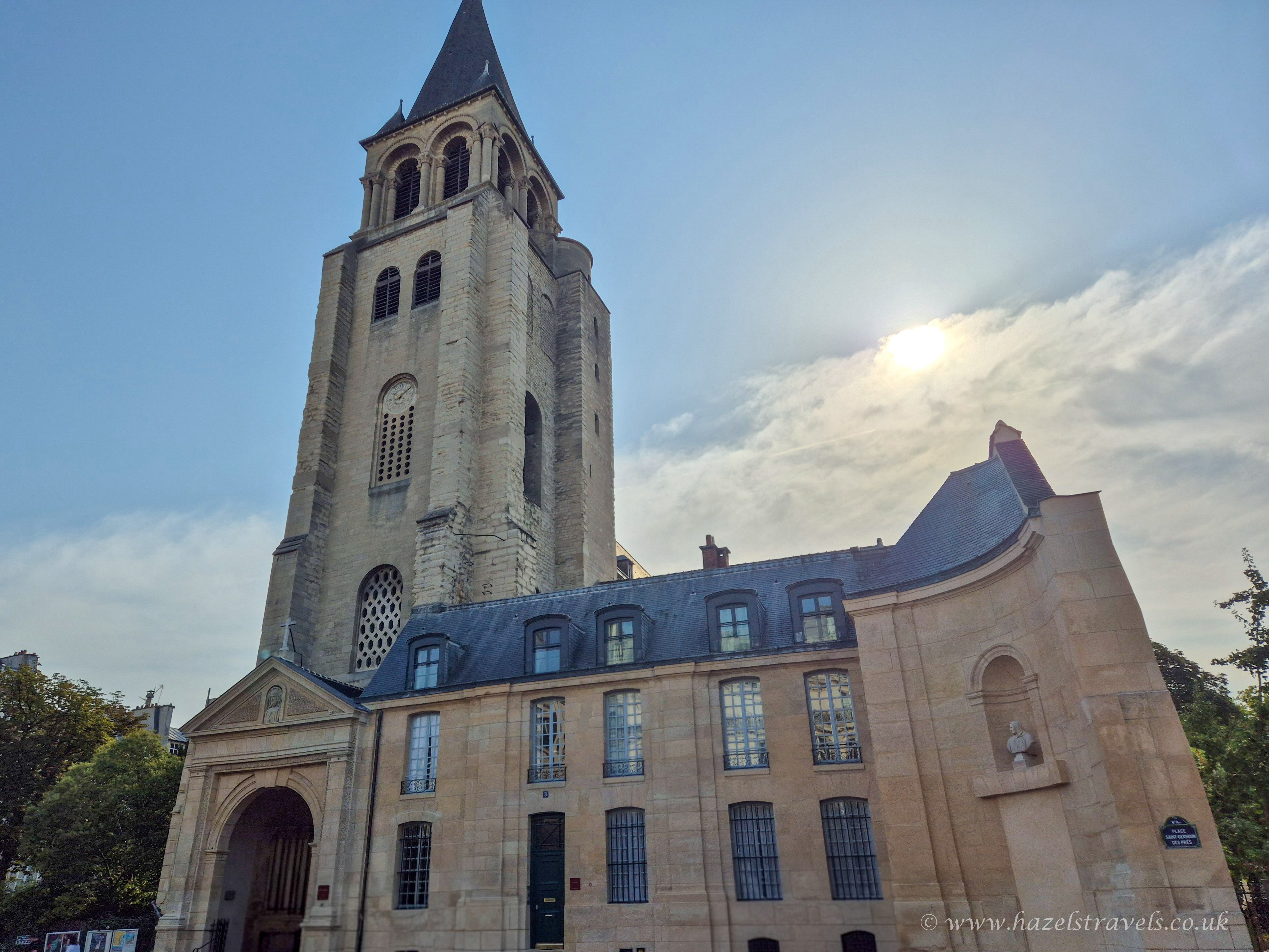 The historic Saint-Germain-des-Prés Church in Paris, captured under a soft afternoon sun with its tall Romanesque bell tower and stone façade.