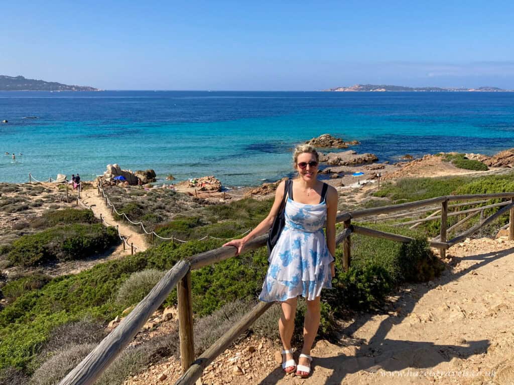 La Maddalena viewpoint, Sardinia - Woman standing at a scenic viewpoint overlooking turquoise sea and rugged coastline.