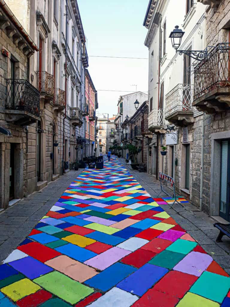 Art street in Tempio Pausania, Sardinia — Colourful woven carpet installation stretching down a traditional Sardinian street.