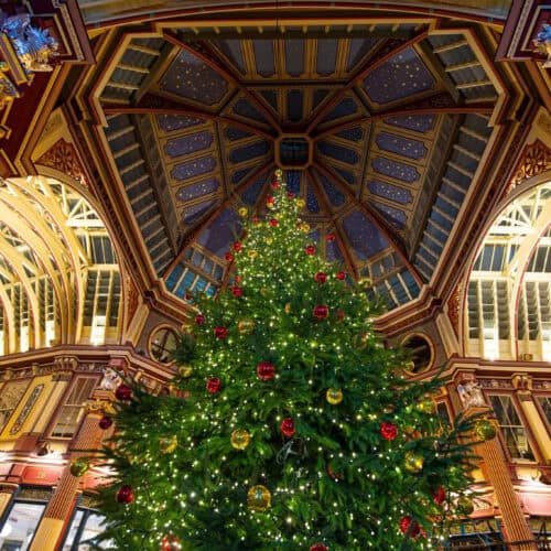 Christmas tree inside Leadenhall Market in London, with ornate Victorian architecture and festive decorations.