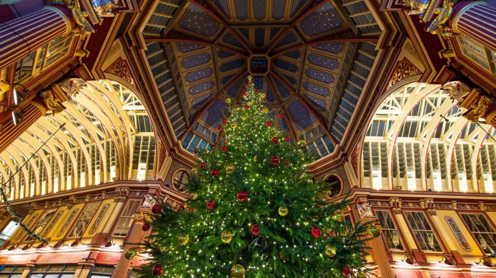 Christmas tree inside Leadenhall Market in London, with ornate Victorian architecture and festive decorations.
