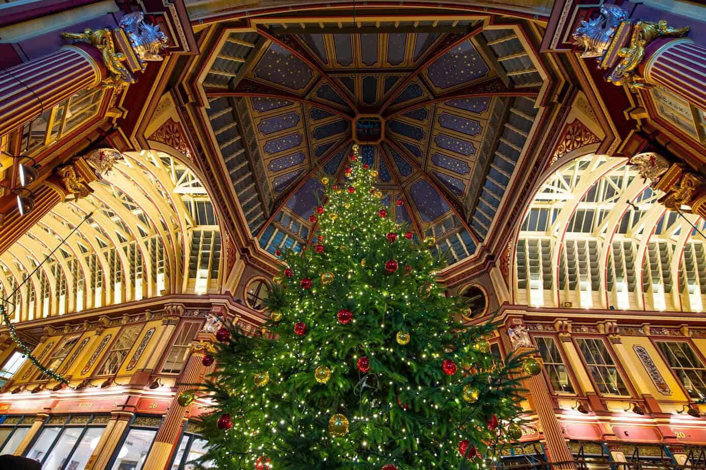 Christmas tree inside Leadenhall Market in London, with ornate Victorian architecture and festive decorations.