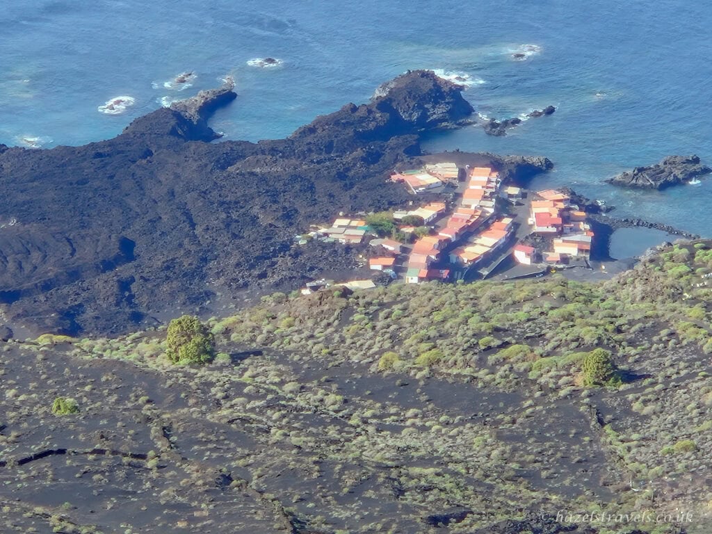 Aerial view of Puerto de Tazacorte nestled on volcanic cliffs by the sea, clearly showing the damage caused by the 2021 Cumbre Vieja eruption.