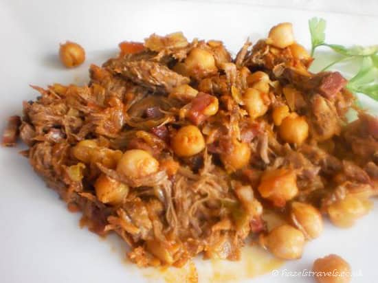 Ropa Vieja chickpea stew dish from the Canary Islands on a white plate with a small piece of greenery in the corner.