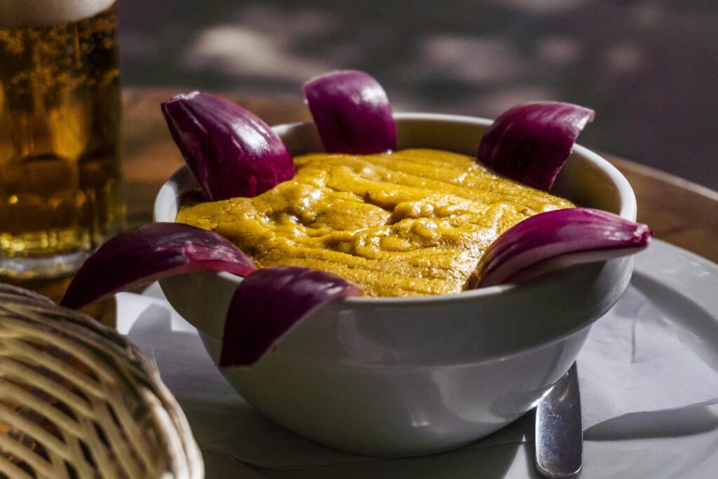 Bowl of gofio, a traditional roasted grain flour dish from the Canary Islands, surrounded by raw red onions dipped in.