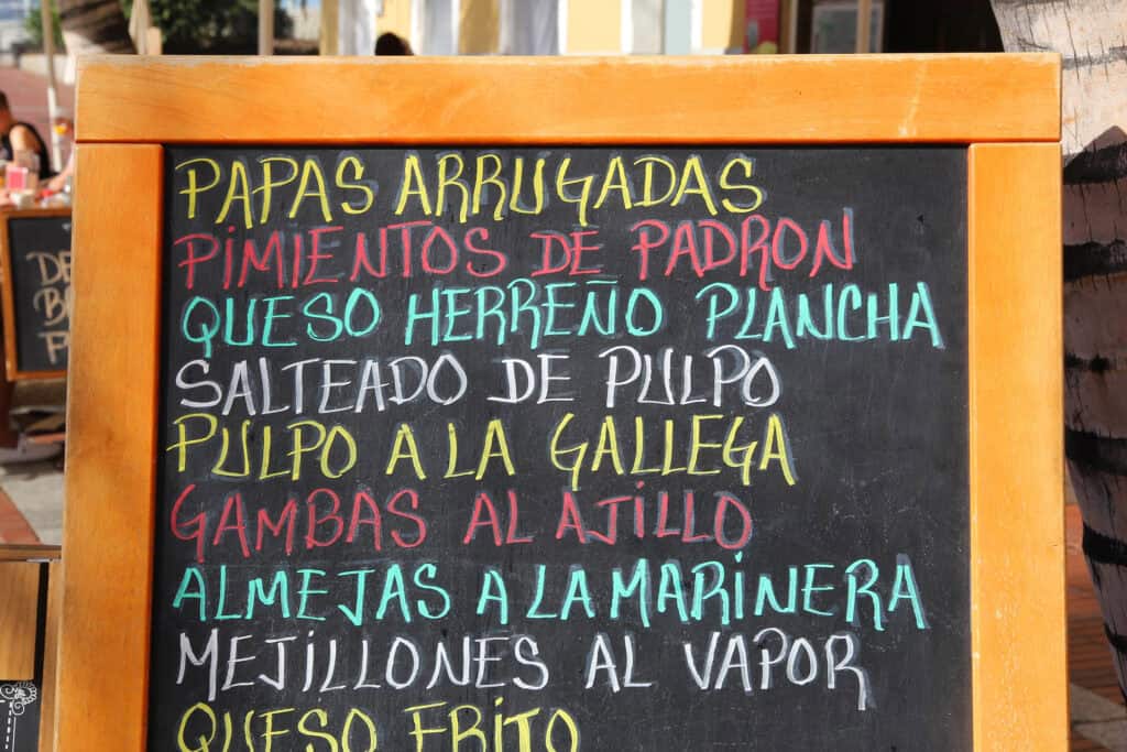 Restaurant chalkboard menu in Spanish listing typical Canarian dishes such as papas arrugadas and pulpo a la gallega.