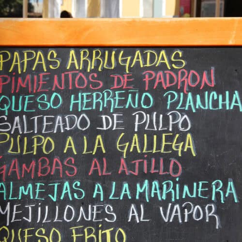 Restaurant chalkboard menu in Spanish listing typical Canarian dishes such as papas arrugadas and pulpo a la gallega.
