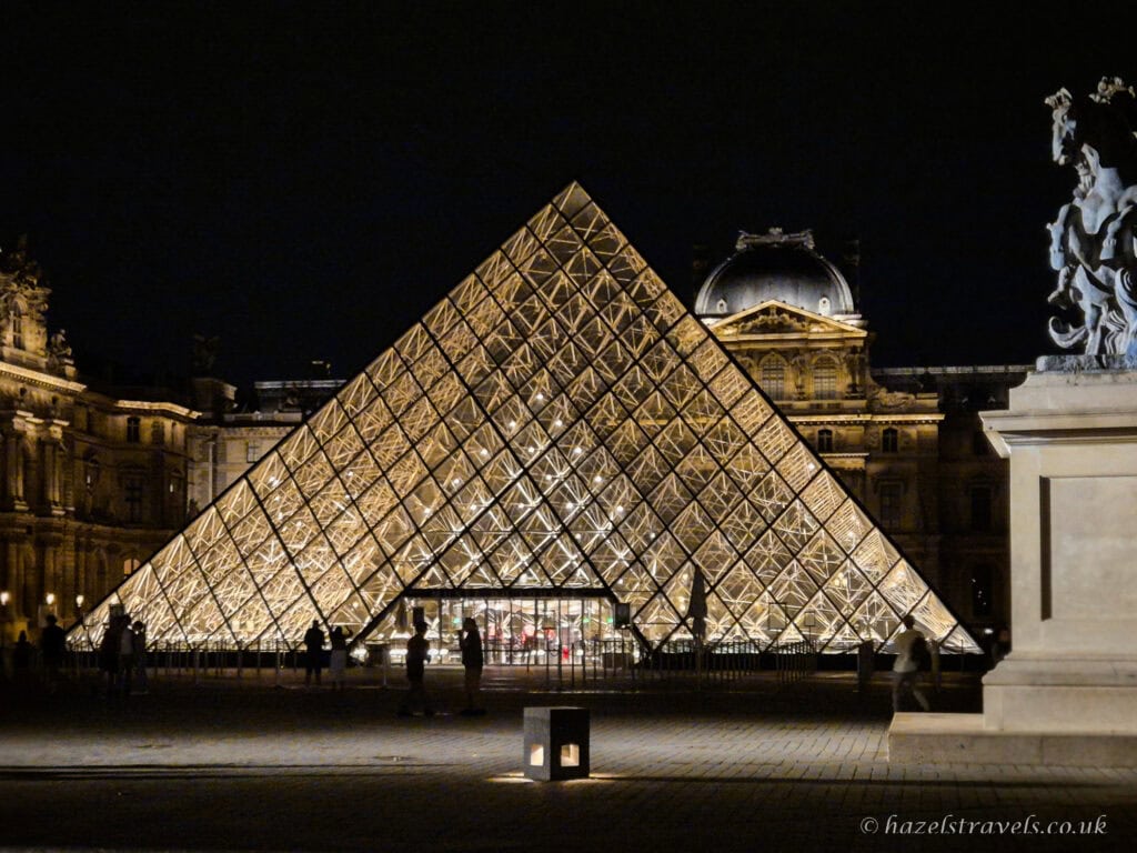 Louvre Pyramid at night, Paris — Glass pyramid illuminated against the dark sky in the Louvre courtyard.