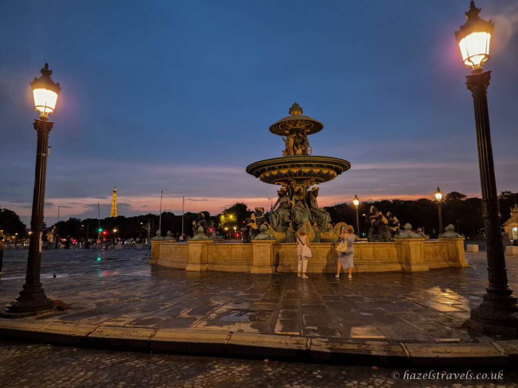 Place de la Concorde fountain, Paris — Illuminated fountain with water cascading under the twilight sky.