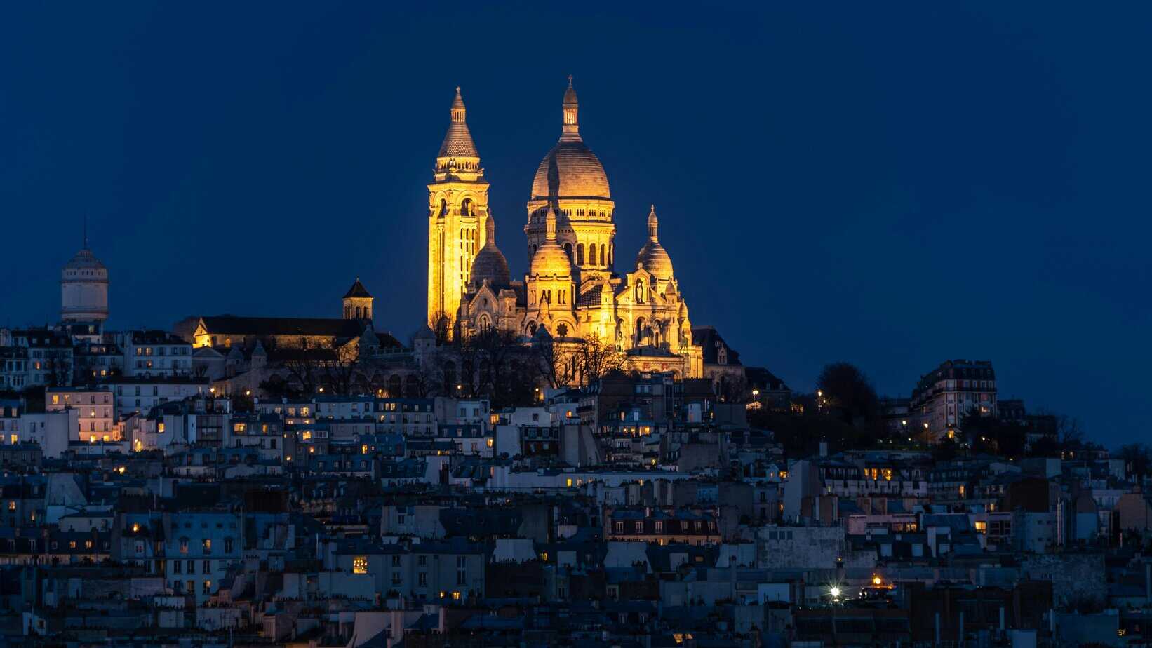Sacré-Cœur Basilica at night, Paris — Golden-lit domes of the basilica shining over the Montmartre skyline.