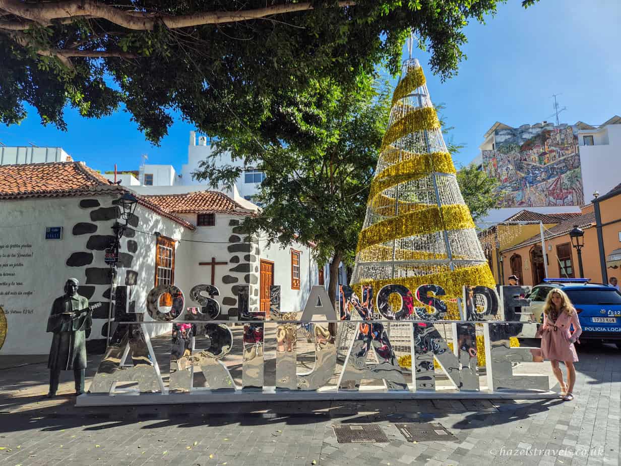 Town square in Los LLanos in Palma with people walking near a large Christmas tree and colonial-style buildings.