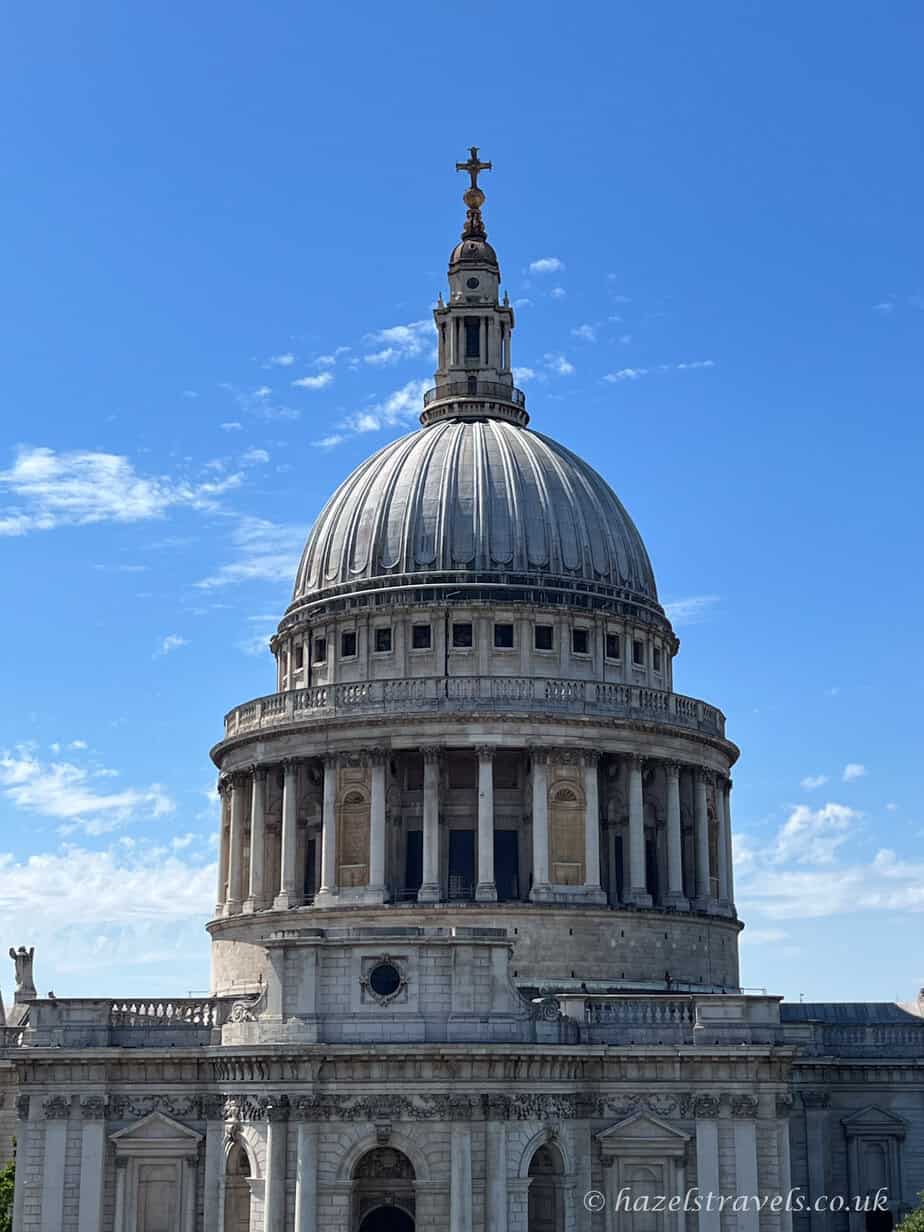St Paul’s Cathedral dome and stone façade against a bright blue sky with light clouds.