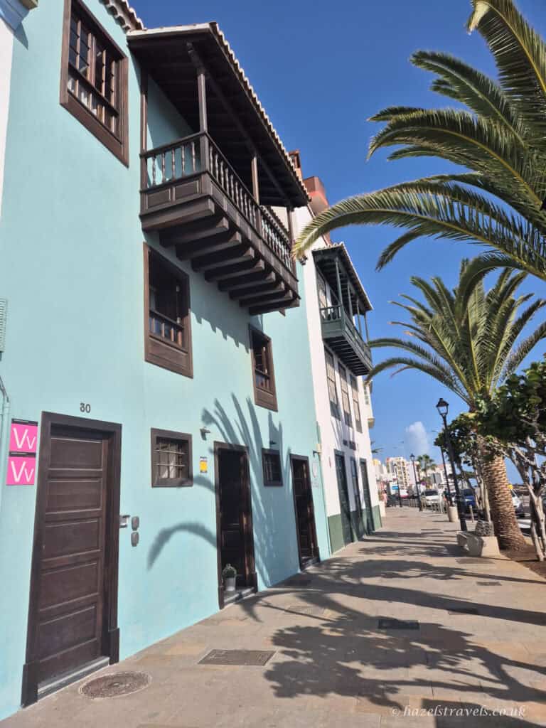 Colourful pastel houses and palm trees along a sunny street in Santa Cruz de La Palma, Canary Islands.