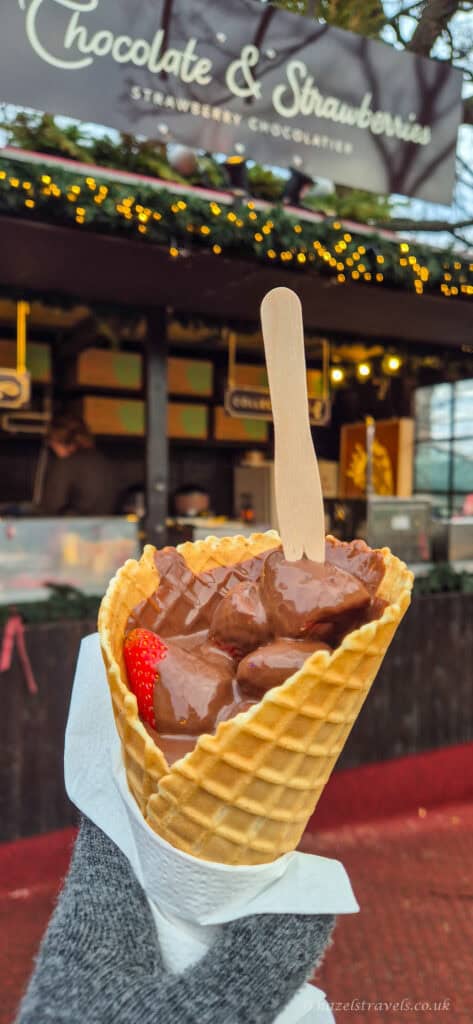 Chocolate-covered strawberries served in a waffle cone at the Edinburgh Christmas Market, with melted chocolate topping and a wooden fork