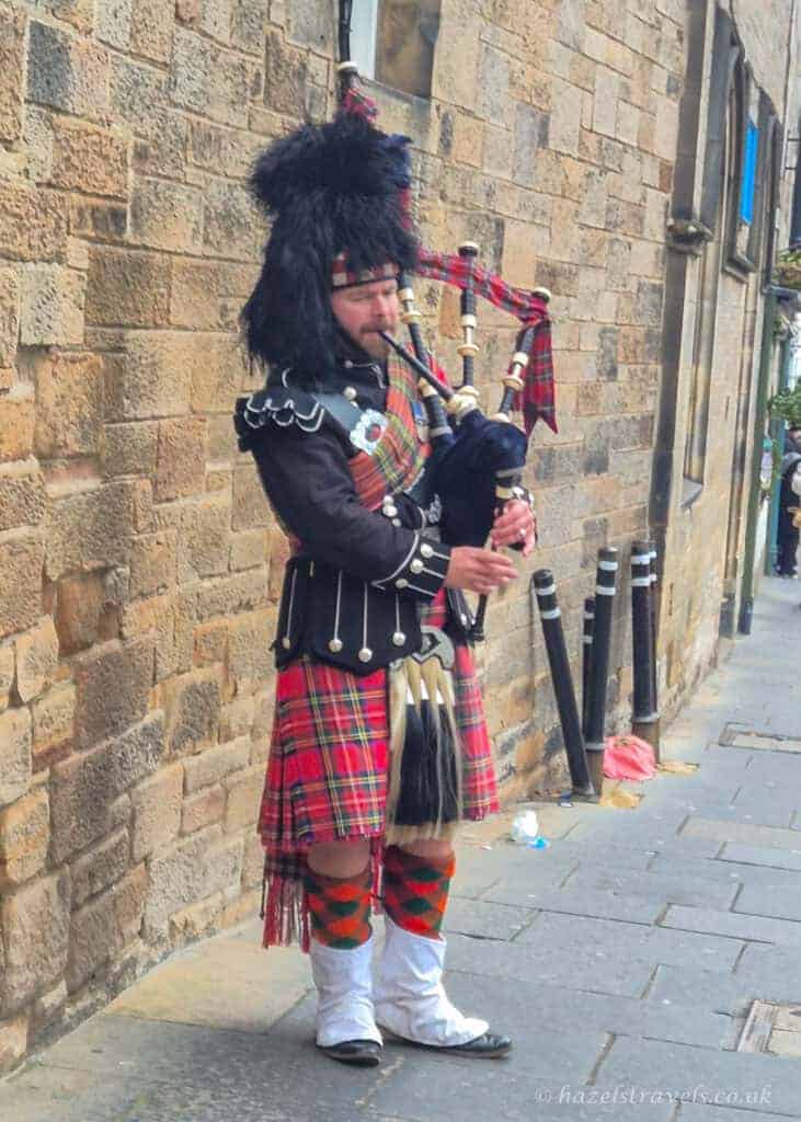 Street performer playing bagpipes in traditional Highland dress on the Royal Mile in Edinburgh