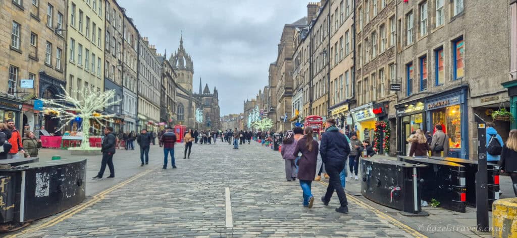 Royal Mile in Edinburgh during the festive season, with Christmas lights, historic stone buildings and people walking along the cobbled street
