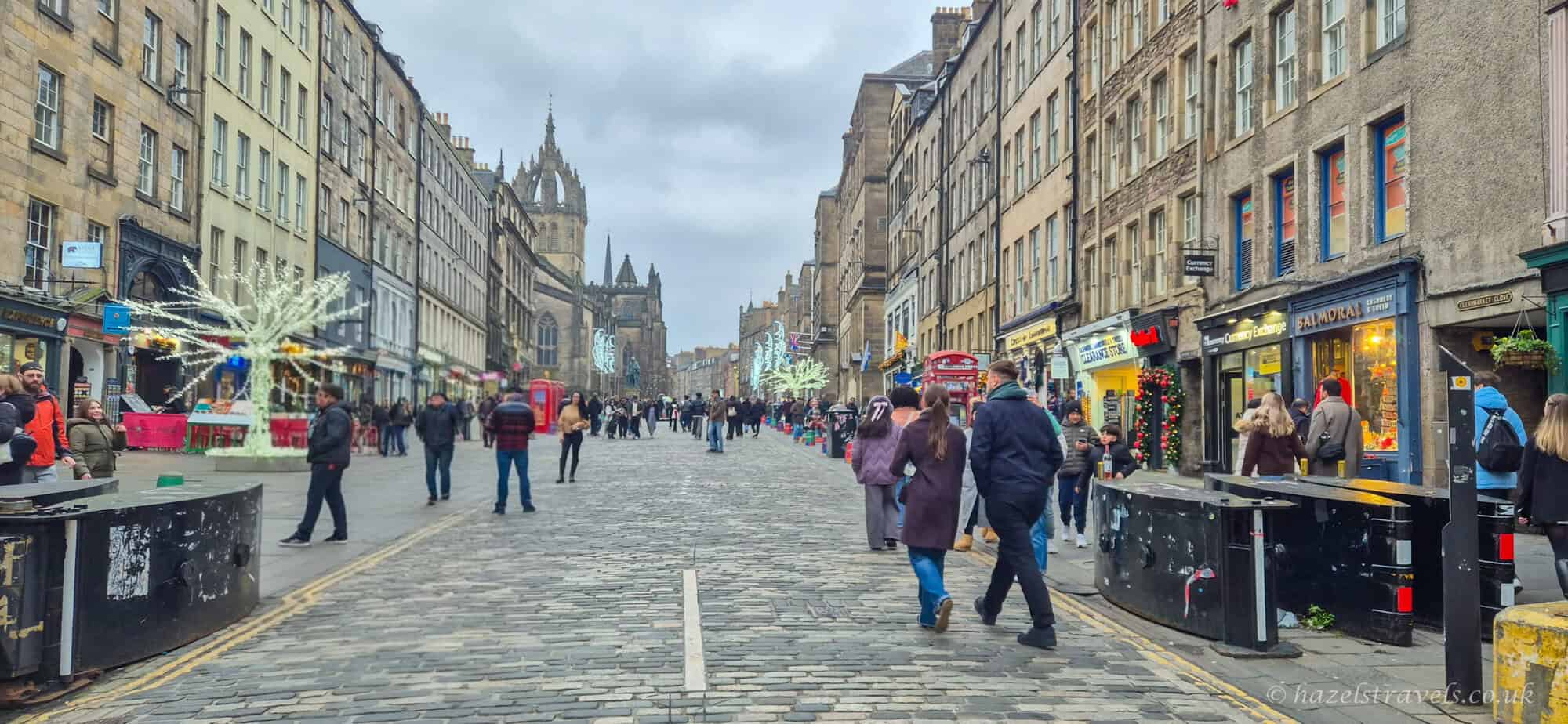 Royal Mile in Edinburgh during the festive season, with Christmas lights, historic stone buildings and people walking along the cobbled street