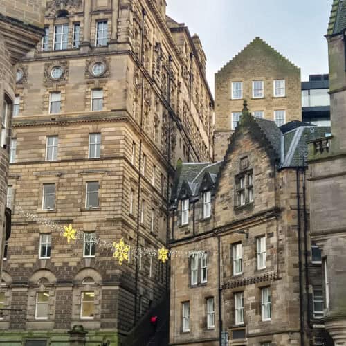 Historic stone buildings in Edinburgh’s Old Town with Christmas lights strung between the streets