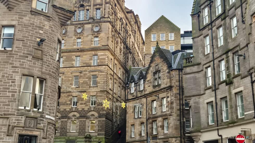 Historic stone buildings in Edinburgh’s Old Town with Christmas lights strung between the streets