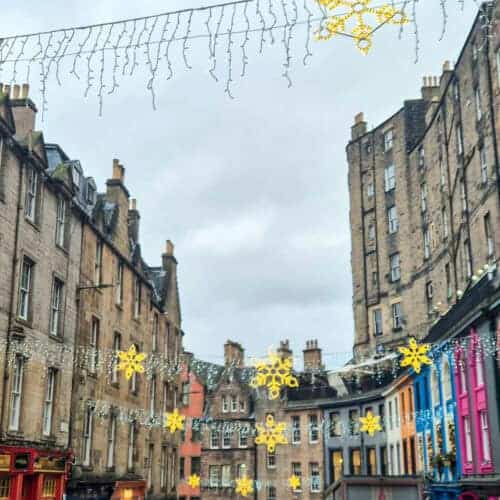 Victoria Street in Edinburgh decorated with hanging snowflake Christmas lights, colourful shopfronts and historic stone buildings