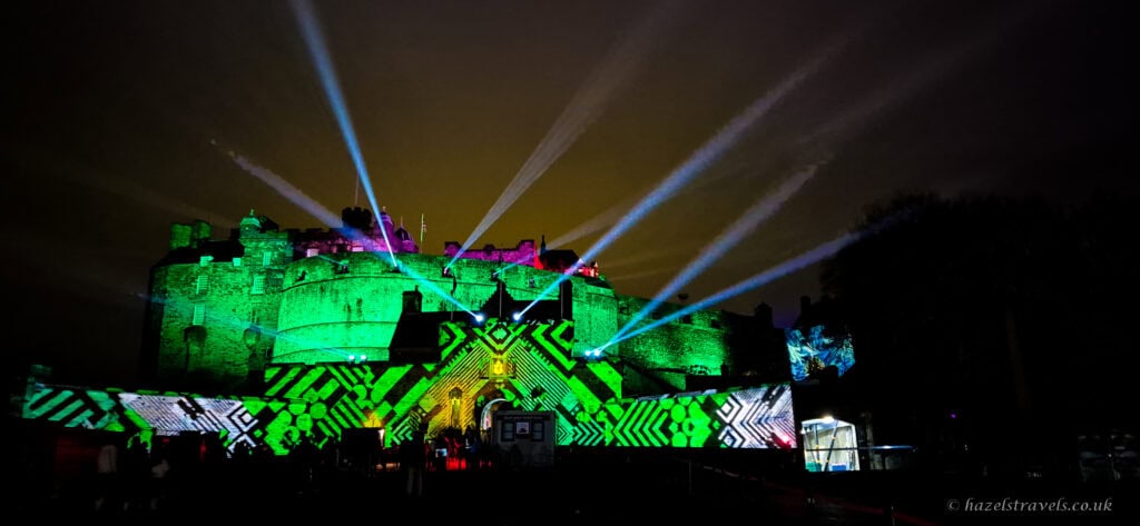 Edinburgh Castle illuminated with green light projections and beams during a winter light show at night
