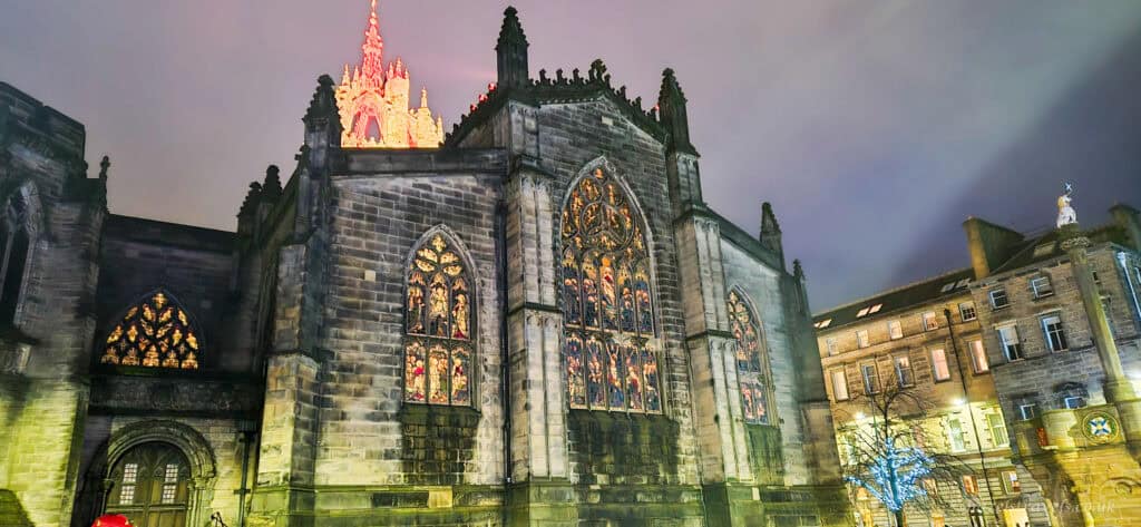 St Giles’ Cathedral lit up at night in Edinburgh, with glowing stained glass windows and the crown spire illuminated against the evening sky