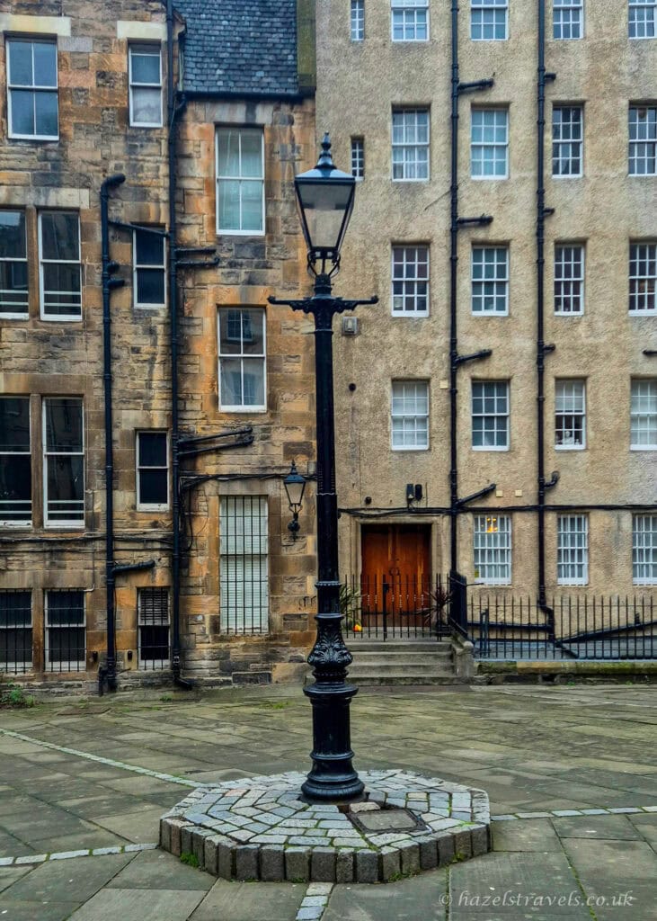 Traditional black lamppost in a quiet courtyard in Edinburgh’s Old Town, surrounded by historic stone buildings
