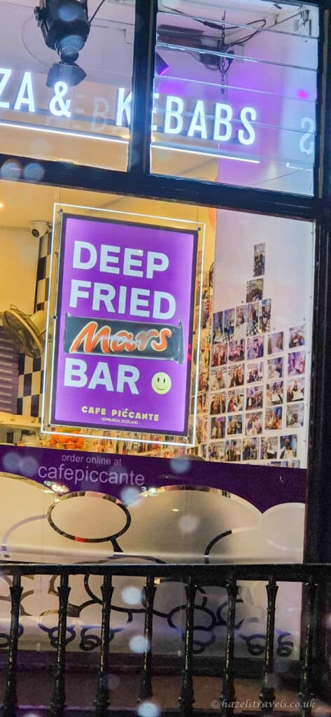 Neon sign advertising a deep fried Mars bar in a café window in Edinburgh at night