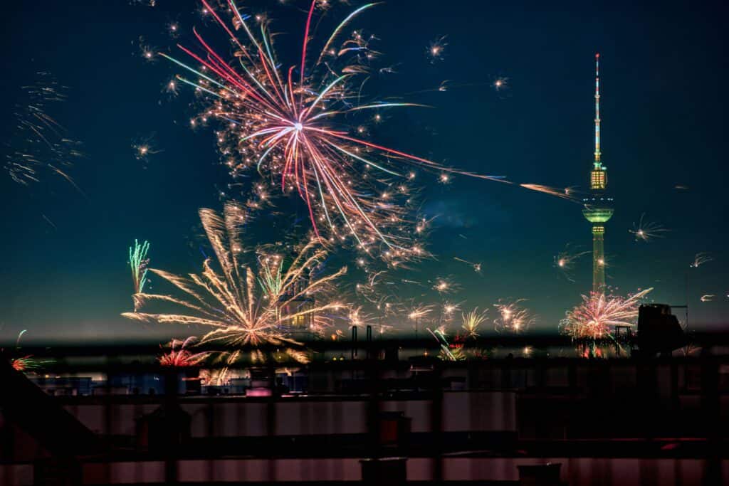 New Year’s Eve fireworks lighting up the Berlin skyline at night, with colourful bursts exploding above the city and the Fernsehturm TV Tower glowing in the background