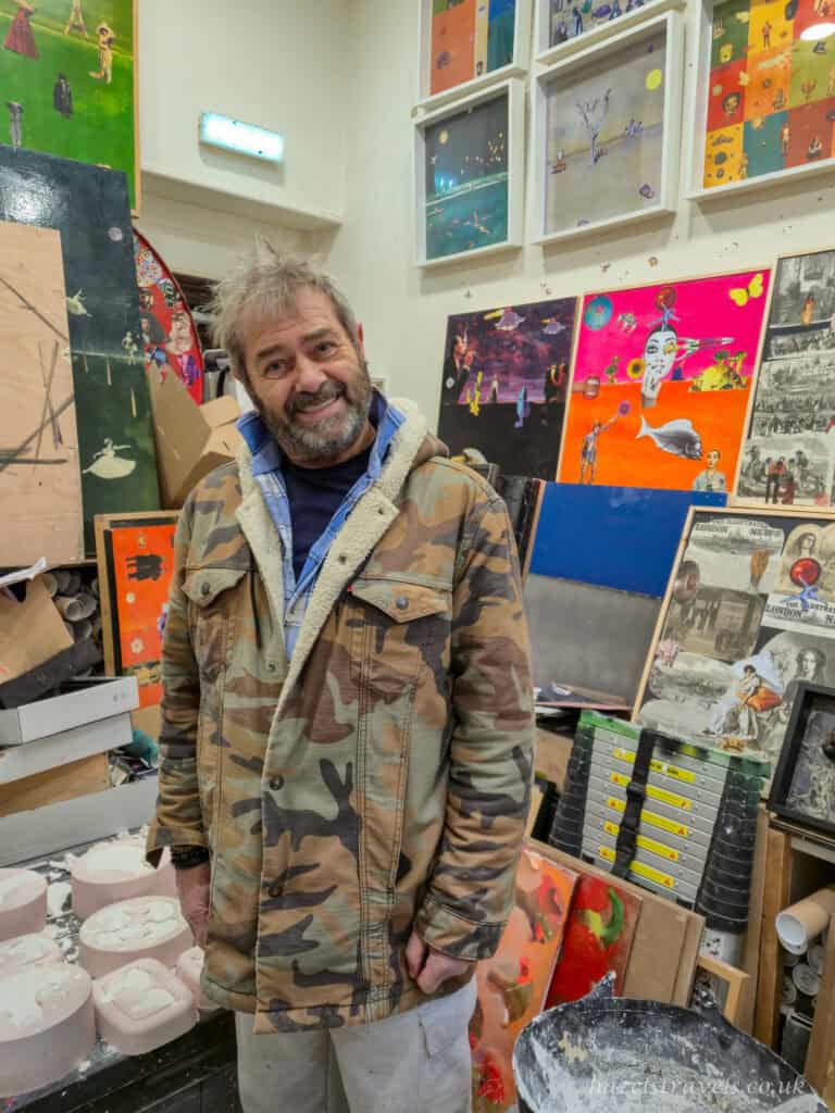 Artist standing in his Shoreditch studio surrounded by colourful mixed-media artworks and moulds, known for creating playful broccoli-themed art pieces